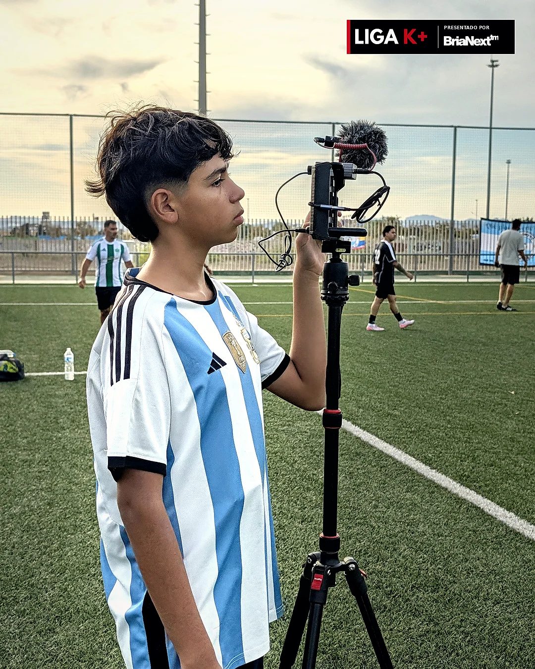 Operador grabando contenido deportivo junto al campo de fútbol